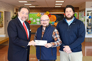 Two PARSS representatives handing a check to a teacher