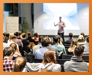 People in an auditorium listening to a presenter